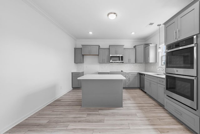 2582 Rafiki Dr, Clarksville, TN 37042 - kitchen featuring appliances with stainless steel finishes, gray cabinets, crown molding, a center island, and tasteful backsplash