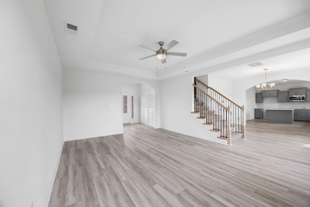 2582 Rafiki Dr, Clarksville, TN 37042 - unfurnished living room featuring a raised ceiling, stairway, arched walkways, light wood-style flooring, and ceiling fan