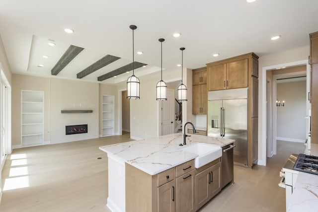 5962 Hunt Valley Dr, Spring Hill, TN 37174 - kitchen featuring stainless steel appliances, a sink, light wood-style flooring, light stone counters, and decorative light fixtures