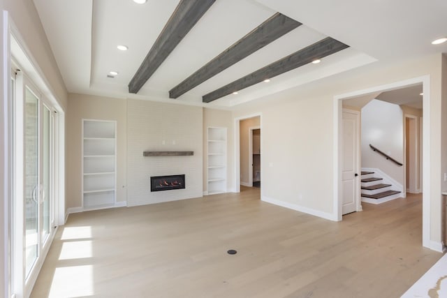 5962 Hunt Valley Dr, Spring Hill, TN 37174 - unfurnished living room with light wood-style flooring, baseboards, beamed ceiling, a fireplace, and stairs