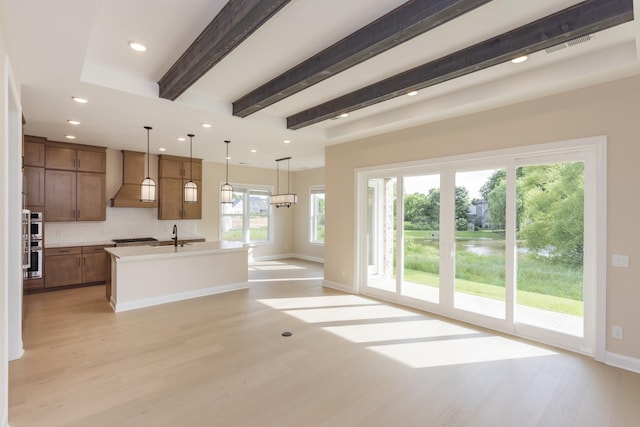 5962 Hunt Valley Dr, Spring Hill, TN 37174 - kitchen featuring light wood-style flooring, decorative backsplash, baseboards, an island with sink, and custom range hood