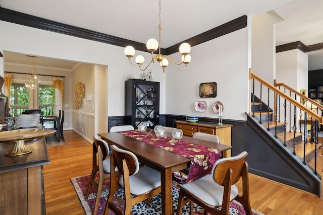 6781 Autumnwood Dr, Nashville, TN 37221 - dining space featuring crown molding, a chandelier, wainscoting, light wood-style floors, and stairway