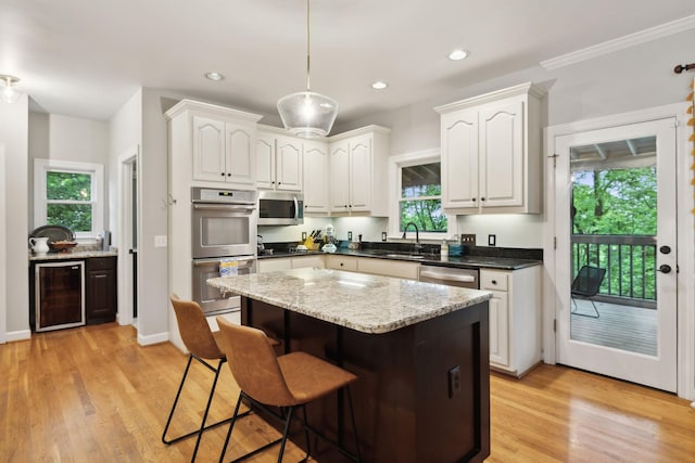 6781 Autumnwood Dr, Nashville, TN 37221 - kitchen with beverage cooler, appliances with stainless steel finishes, a breakfast bar area, light wood-style flooring, and white cabinetry