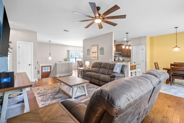 2157 Christina Ct, Hermitage, TN 37076 - living room featuring ceiling fan, light wood-style flooring, baseboards, and a chandelier