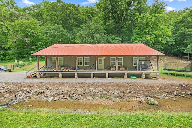 333 Cubbins Hollow Rd, Dowelltown, TN 37059 - view of front of house with covered porch, a trampoline, metal roof, and a view of trees