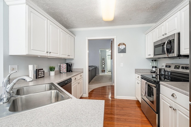 5026 Claude Dr, Smyrna, TN 37167 - kitchen featuring appliances with stainless steel finishes, a sink, white cabinets, light wood-style flooring, and ornamental molding