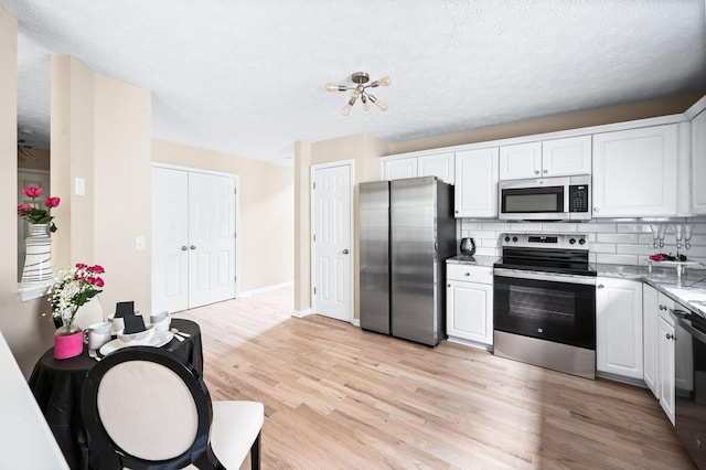 2210 Falcon Creek Dr, Franklin, TN 37067 - kitchen with appliances with stainless steel finishes, tasteful backsplash, light wood-style floors, white cabinets, and a textured ceiling