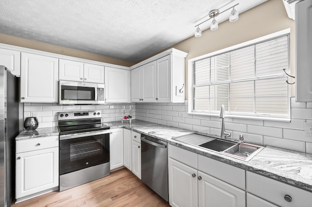 2210 Falcon Creek Dr, Franklin, TN 37067 - kitchen with stainless steel appliances, a sink, white cabinetry, a textured ceiling, and backsplash