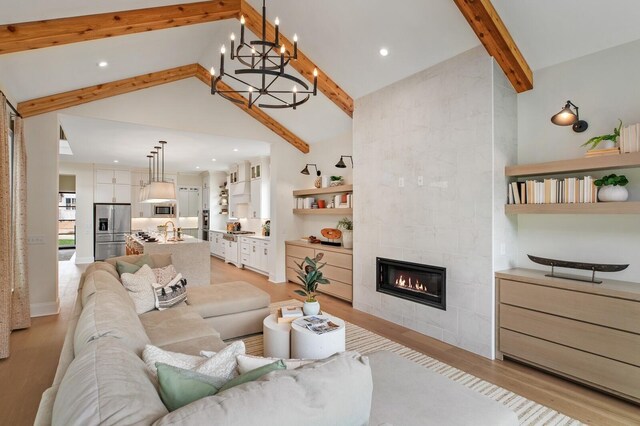 7271 Murrel Dr, Franklin, TN 37064 - living area featuring beamed ceiling, light wood-style flooring, high vaulted ceiling, a tile fireplace, and a chandelier