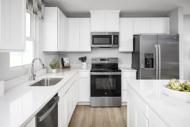 1680 Laurel St, Gallatin, TN 37066 - kitchen featuring appliances with stainless steel finishes, a sink, light wood-style flooring, white cabinets, and light countertops
