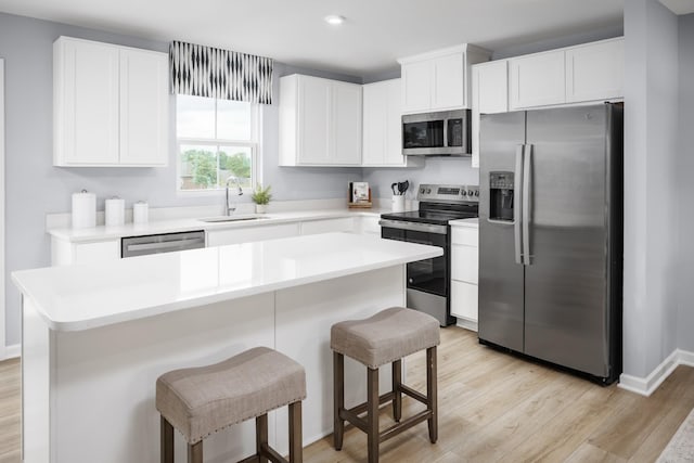 1680 Laurel St, Gallatin, TN 37066 - kitchen featuring appliances with stainless steel finishes, a sink, light wood finished floors, a breakfast bar area, and white cabinetry