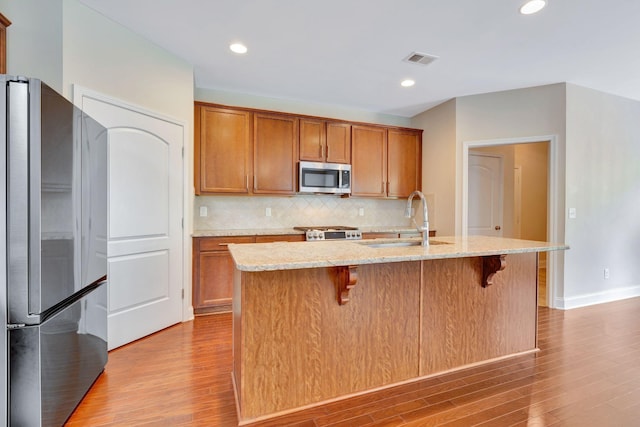 356 Irvine Ln, Franklin, TN 37064 - kitchen featuring appliances with stainless steel finishes, a sink, wood finished floors, decorative backsplash, and light stone countertops
