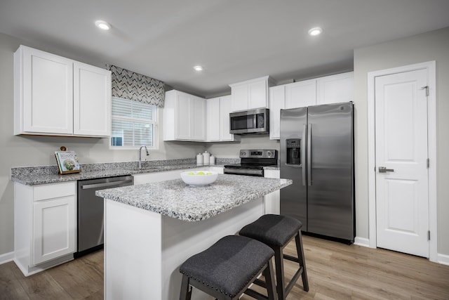 1296 Laurel St, Gallatin, TN 37066 - kitchen featuring appliances with stainless steel finishes, a kitchen breakfast bar, white cabinetry, a center island, and light stone counters