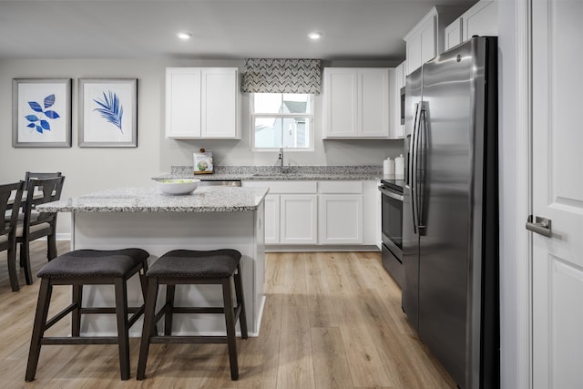 1296 Laurel St, Gallatin, TN 37066 - kitchen featuring stainless steel appliances, white cabinets, light stone counters, a sink, and a kitchen breakfast bar