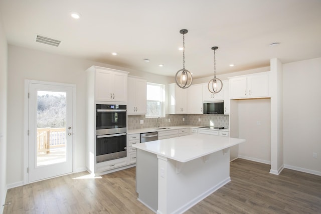 3263 Kemp Dr, Hermitage, TN 37076 - kitchen with black appliances, decorative backsplash, white cabinetry, a kitchen island, and recessed lighting