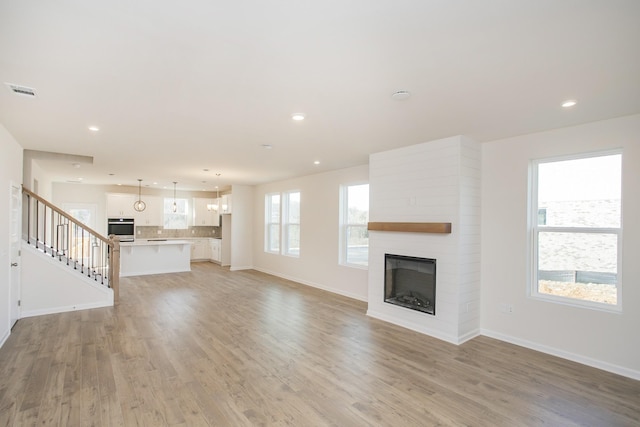 3263 Kemp Dr, Hermitage, TN 37076 - unfurnished living room featuring a large fireplace, light wood-style flooring, baseboards, stairs, and recessed lighting