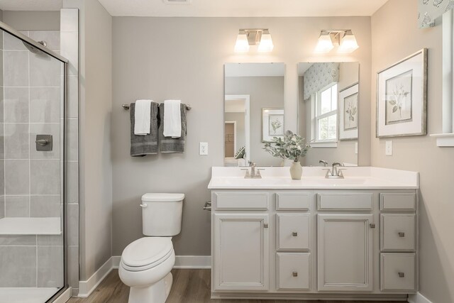 1173 Savannah Ave, Gallatin, TN 37066 - bathroom with double vanity, toilet, a tile shower, and wood finished floors