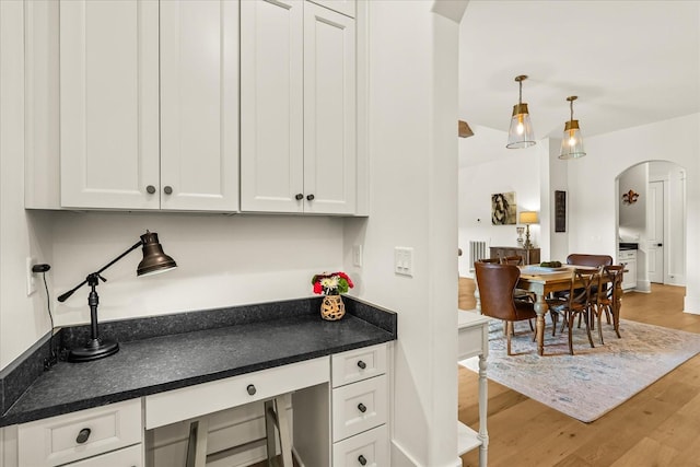 1750 Barrow Ln, Brentwood, TN 37027 - kitchen featuring arched walkways, dark countertops, wood finished floors, white cabinetry, and decorative light fixtures