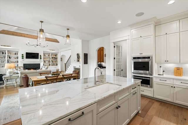 1750 Barrow Ln, Brentwood, TN 37027 - kitchen featuring a sink, arched walkways, open floor plan, wood finished floors, and stainless steel double oven