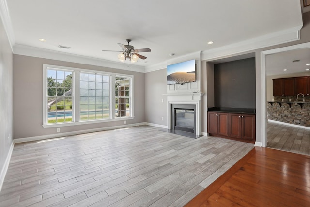 102 Oglethorpe Ave, Gallatin, TN 37066 - unfurnished living room featuring a ceiling fan, a glass covered fireplace, light wood finished floors, ornamental molding, and baseboards