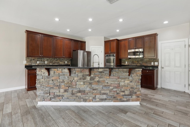 102 Oglethorpe Ave, Gallatin, TN 37066 - kitchen featuring stainless steel appliances, dark countertops, light wood finished floors, a large island, and tasteful backsplash
