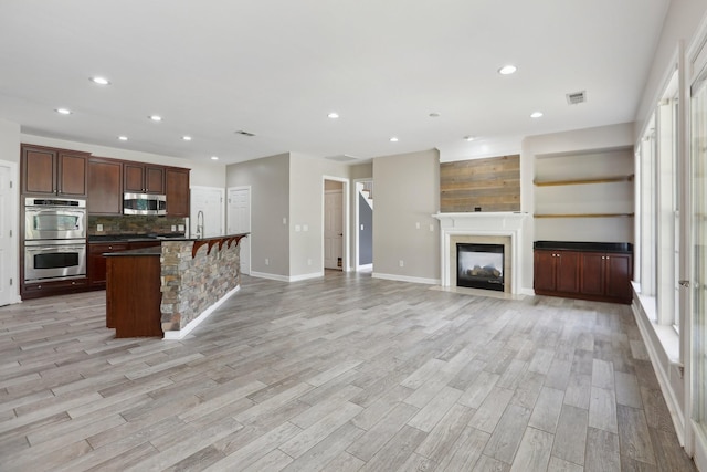 102 Oglethorpe Ave, Gallatin, TN 37066 - kitchen featuring stainless steel appliances, decorative backsplash, light wood-style flooring, dark countertops, and recessed lighting