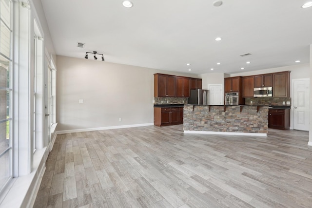 102 Oglethorpe Ave, Gallatin, TN 37066 - kitchen with stainless steel appliances, dark countertops, backsplash, light wood-style flooring, and a breakfast bar