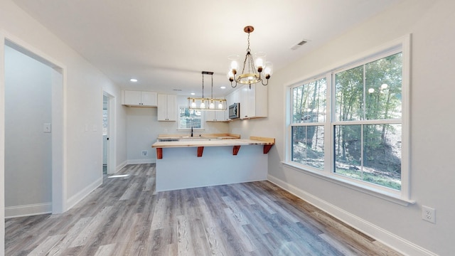 9716 Campbellsville Rd, Pulaski, TN 38478 - kitchen featuring a chandelier, stainless steel microwave, a peninsula, white cabinets, and light wood-style flooring