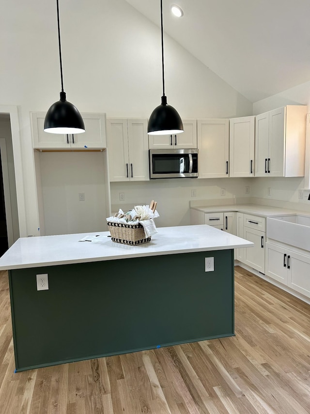 9710 Campbellsville Rd, Pulaski, TN 38478 - kitchen featuring stainless steel microwave, high vaulted ceiling, a center island, white cabinetry, and light wood finished floors