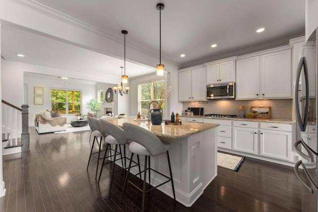 23 Hope Ct, Mount Juliet, TN 37122 - kitchen featuring appliances with stainless steel finishes, crown molding, white cabinets, open floor plan, and light stone counters