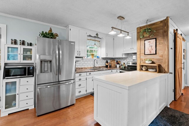 7214 Timberlane Dr, Fairview, TN 37062 - kitchen with stainless steel appliances, a sink, a textured ceiling, a peninsula, and light wood-style flooring