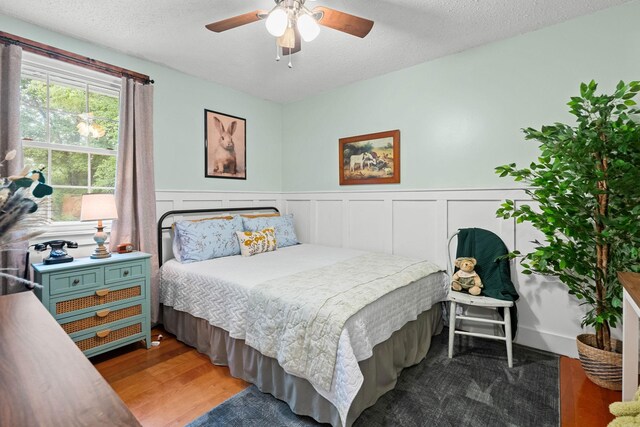 7214 Timberlane Dr, Fairview, TN 37062 - bedroom featuring wood finished floors, a wainscoted wall, a textured ceiling, and ceiling fan
