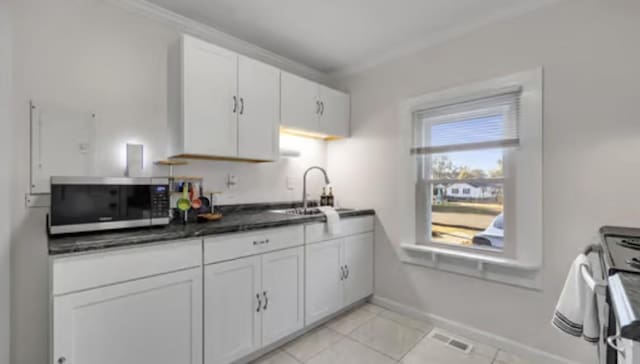 506 Garden St, Mount Pleasant, TN 38474 - kitchen with stainless steel microwave, a sink, white cabinets, light tile patterned floors, and baseboards