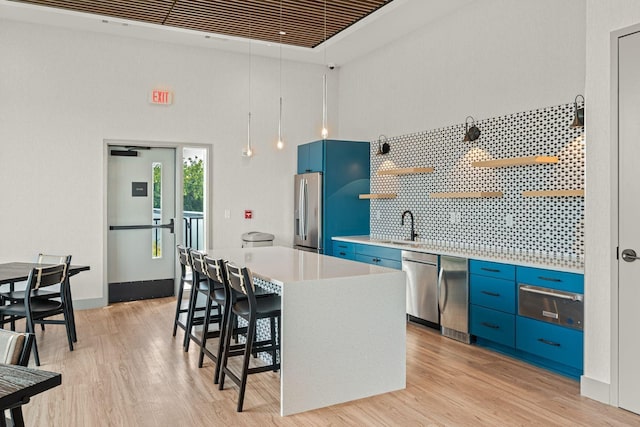 1014 16th Ave S Unit 210, Nashville, TN 37212 - kitchen with blue cabinetry, a warming drawer, appliances with stainless steel finishes, open shelves, and a breakfast bar area