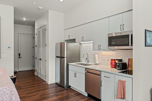 1014 16th Ave S Unit 210, Nashville, TN 37212 - kitchen featuring stainless steel appliances, a sink, dark wood-type flooring, tasteful backsplash, and white cabinets