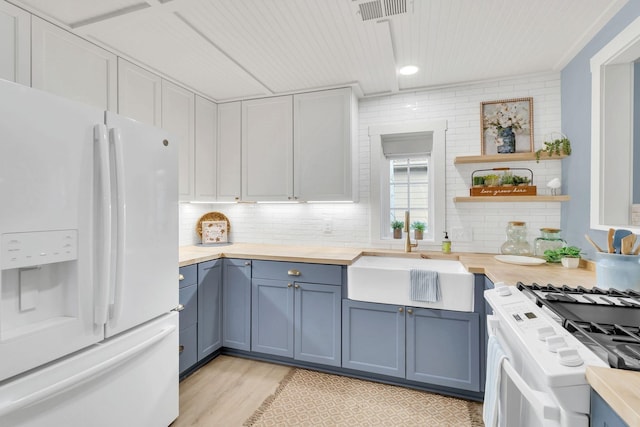 210 Kerr Ave, Murfreesboro, TN 37130 - kitchen with white refrigerator with ice dispenser, a sink, range with gas cooktop, blue cabinetry, and light wood-type flooring