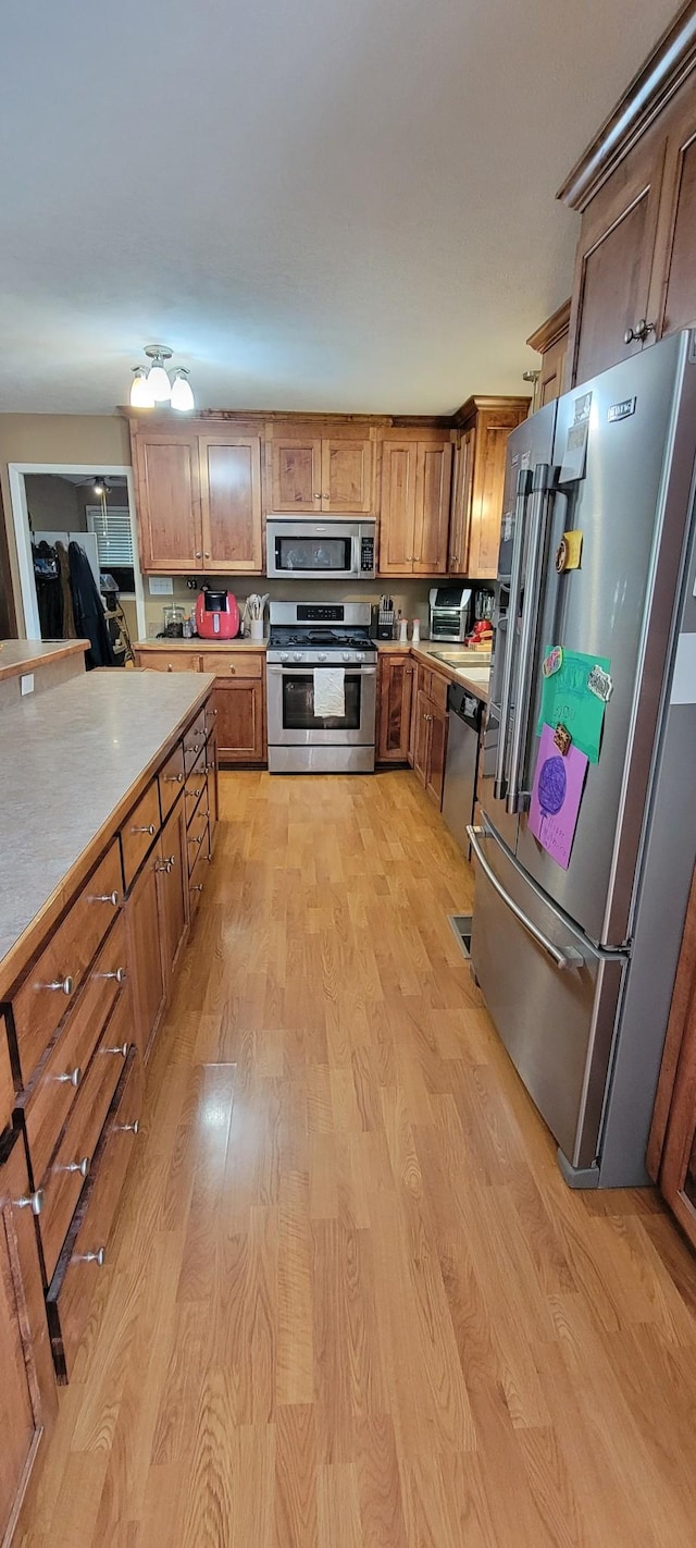 208 Royal Oak Dr, Dickson, TN 37055 - kitchen with appliances with stainless steel finishes, light wood finished floors, light countertops, and brown cabinetry