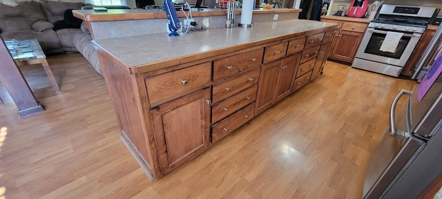208 Royal Oak Dr, Dickson, TN 37055 - kitchen featuring stainless steel range with gas cooktop, light wood finished floors, brown cabinets, and light countertops