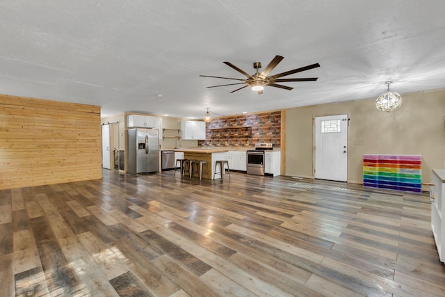 9780 S Lick Creek Rd SW, Lyles, TN 37098 - unfurnished living room featuring wood finished floors, a ceiling fan, wooden walls, a chandelier, and a sink