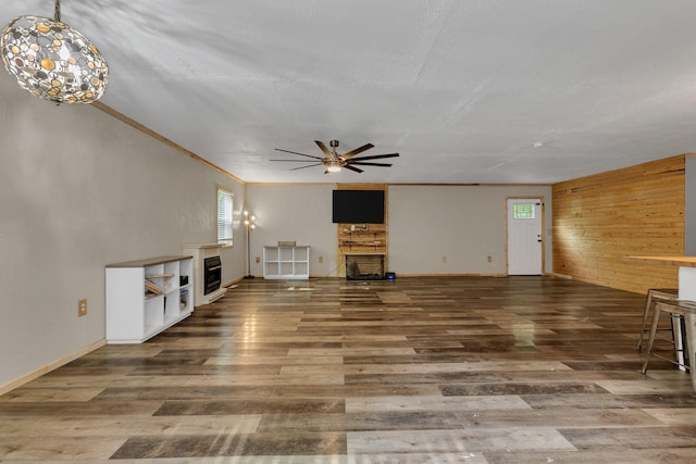9780 S Lick Creek Rd SW, Lyles, TN 37098 - unfurnished living room with a fireplace, wood finished floors, ceiling fan, wooden walls, and baseboards