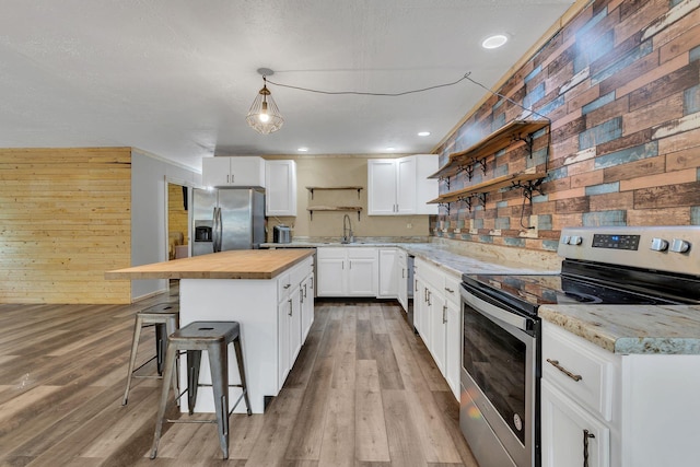 9780 S Lick Creek Rd SW, Lyles, TN 37098 - kitchen featuring appliances with stainless steel finishes, open shelves, wooden counters, wood walls, and a breakfast bar