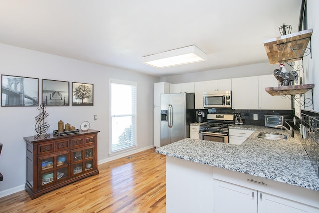 321 Amherst Dr, Murfreesboro, TN 37128 - kitchen with stainless steel appliances, a sink, a peninsula, light stone countertops, and light wood finished floors