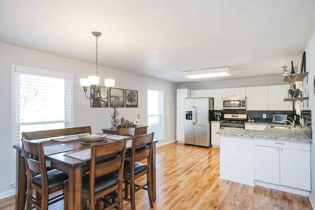 321 Amherst Dr, Murfreesboro, TN 37128 - kitchen with stainless steel appliances, a chandelier, a peninsula, light wood finished floors, and backsplash