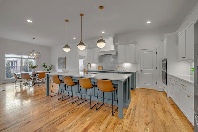 609 Dallas Ct, Murfreesboro, TN 37130 - kitchen featuring custom range hood, a sink, decorative backsplash, light countertops, and an island with sink