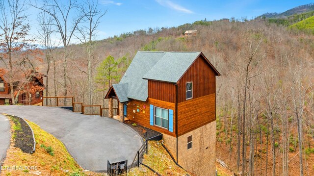 817 Pine Top Ln, Gatlinburg, TN 37738 - view of front of property featuring a shingled roof, a wooded view, and stone siding