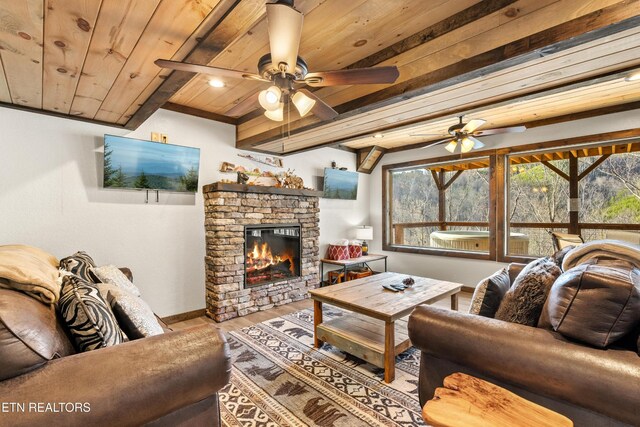 817 Pine Top Ln, Gatlinburg, TN 37738 - living room with wood ceiling with exposed beams, wood finished floors, a ceiling fan, a stone fireplace, and baseboards