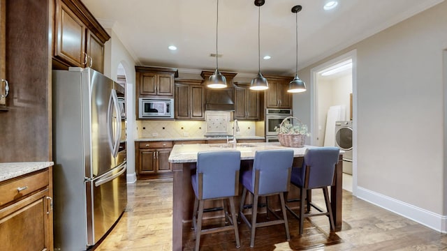 1303 Reynard Dr, Gallatin, TN 37066 - kitchen featuring stainless steel appliances, crown molding, decorative backsplash, an island with sink, and light wood-style floors