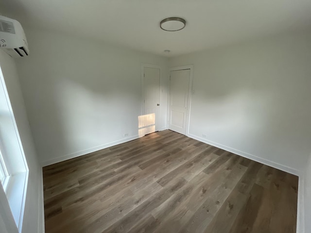 119 Maple Ave, Camden, TN 38320 - unfurnished bedroom featuring dark wood finished floors, a wall unit AC, and baseboards