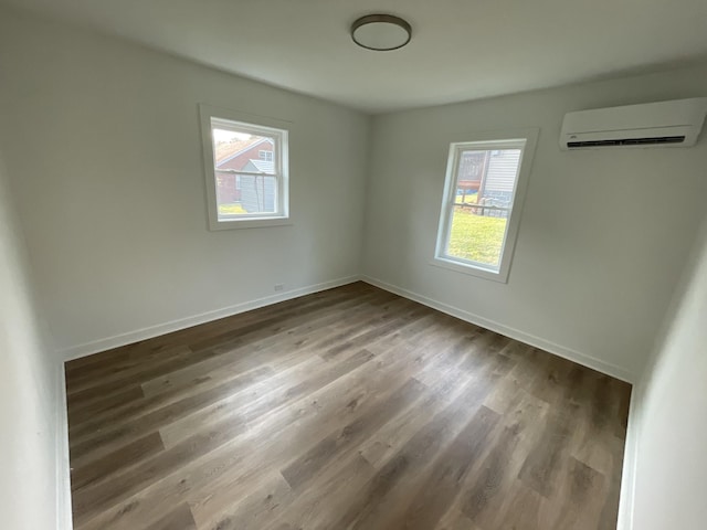 119 Maple Ave, Camden, TN 38320 - unfurnished bedroom with a wall mounted air conditioner, multiple windows, wood finished floors, and baseboards
