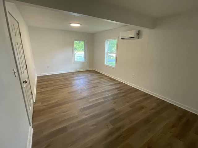 119 Maple Ave, Camden, TN 38320 - empty room with a wall unit AC, dark wood-style flooring, and baseboards